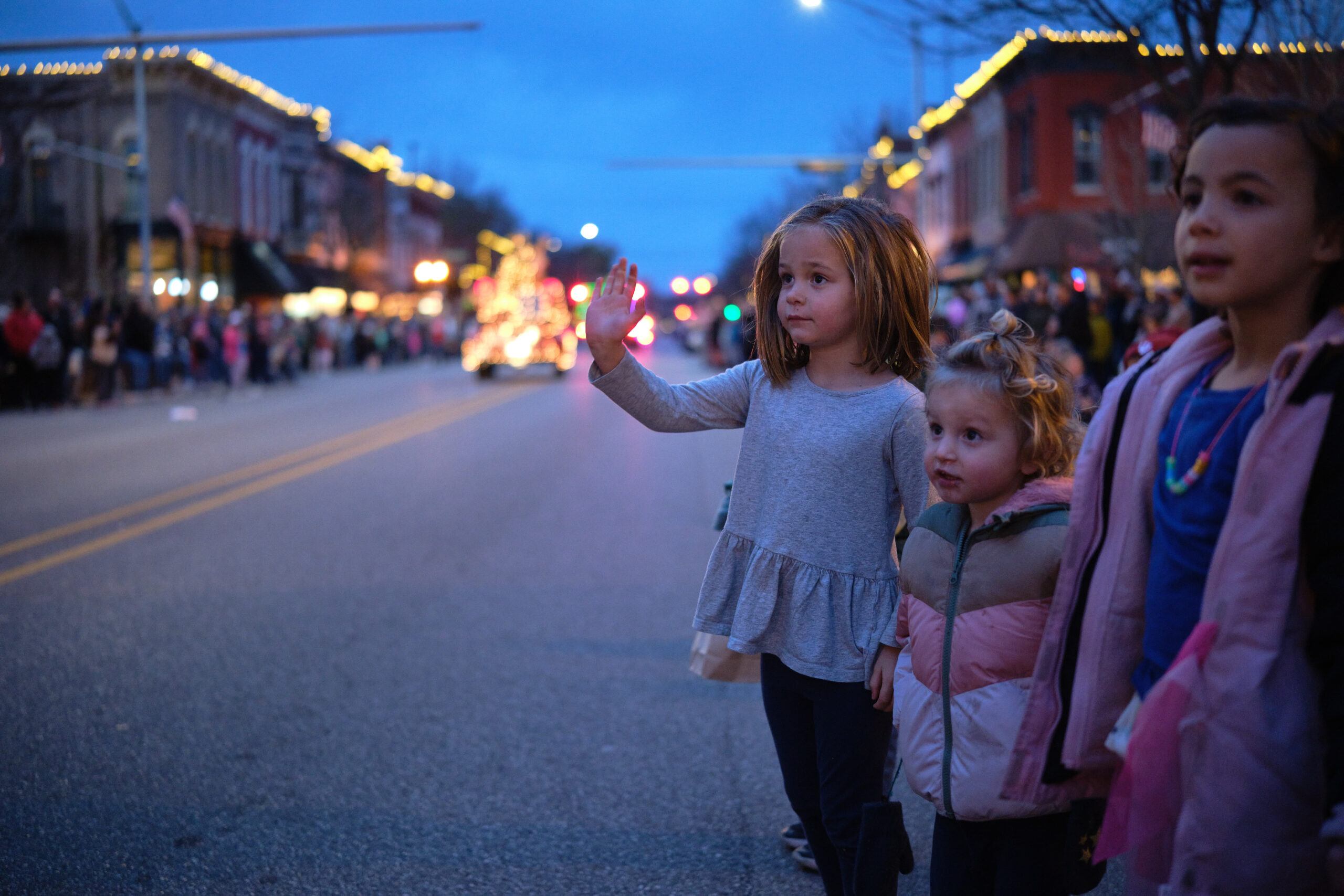 A group of young children waving to lighted floats as the pass by on Main Street