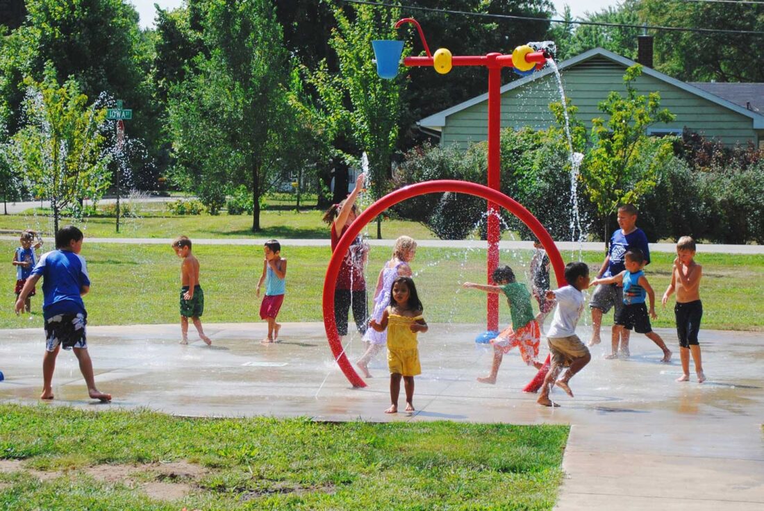 A photo fo the Walnut Park splash pad with kids of all ages playing on a summer day.